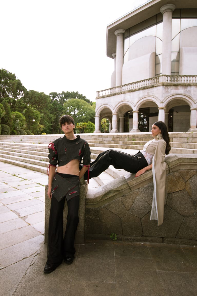 Two II Acto looks on the pavilion steps, one in black with red trim and one with a draped cream panel.