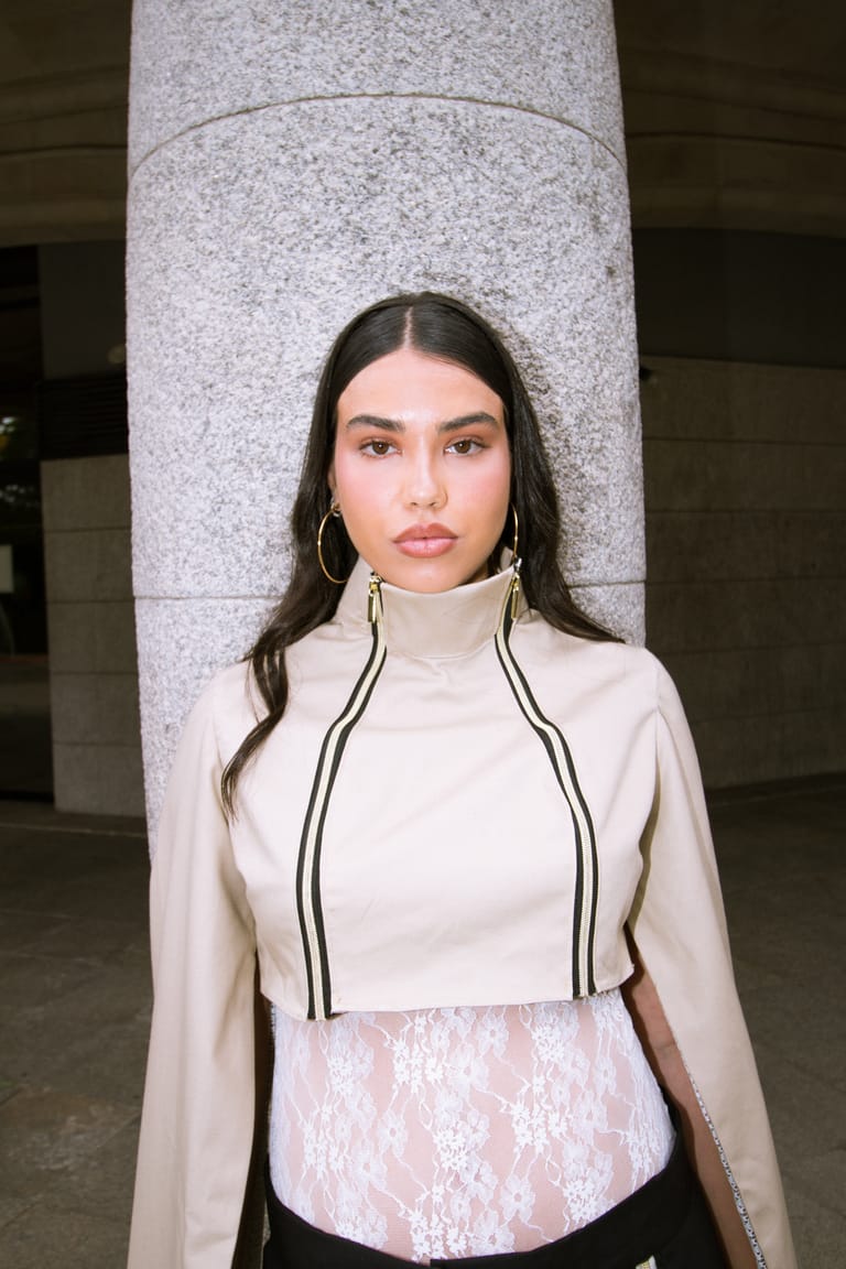 Portrait of an II Acto look: cream high-neck top with a black zip detail over lace.