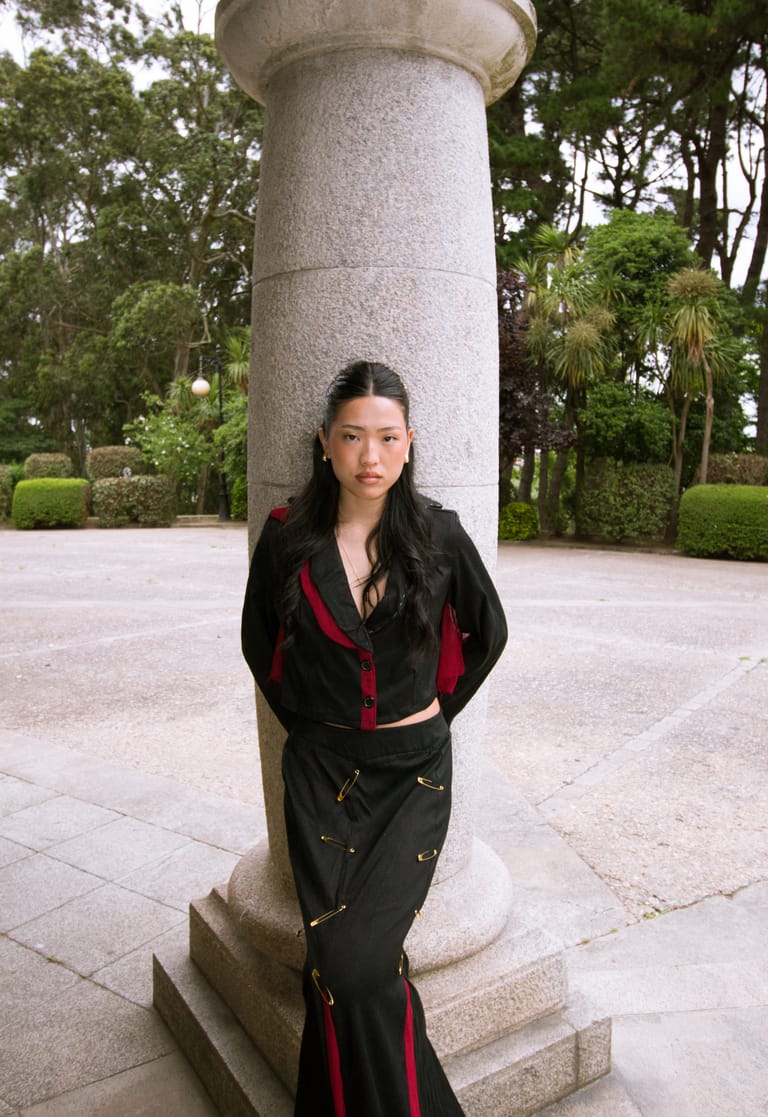 II Acto look standing against a granite column, black with red trim.