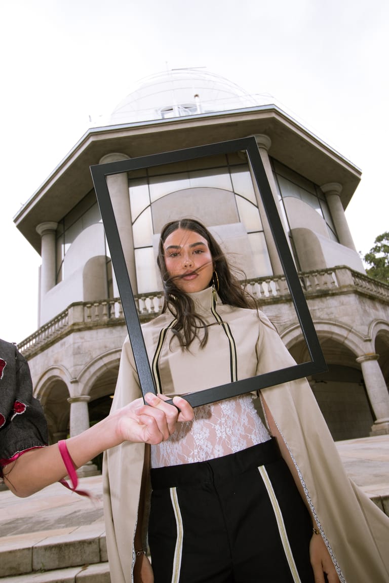 II Acto look holding an empty picture frame in front of the pavilion.